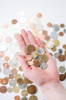 Close-up of a hand holding diverse coins, symbolizing global currency and finance.